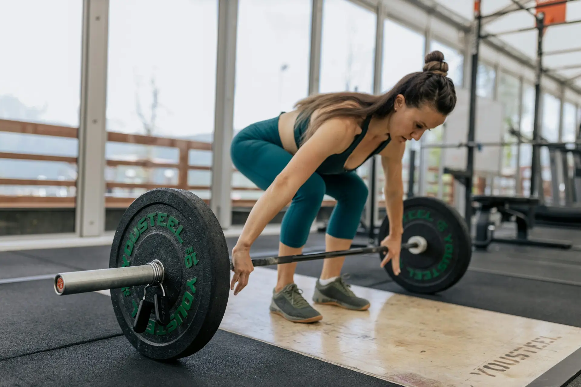Focused woman lifting barbell in gym, showcasing strength and fitness.